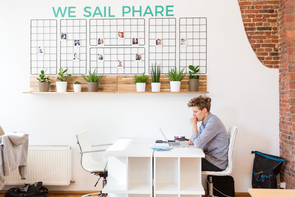 Man working next to the "we sail Phare" board.